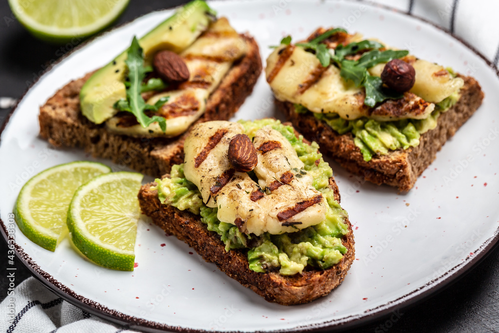 Grilled halloumi sandwich with avocado guacamole, arugula. Toast with grilled cheese and avocado. Healthy food