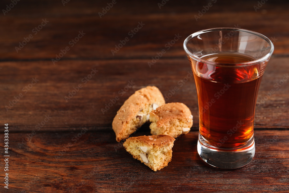 Tasty cantucci and glass of liqueur on wooden table, space for text. Traditional Italian almond biscuits Tasty cantucci and glass of liqueur on wooden table, space for text. Traditional Italian almond biscuits