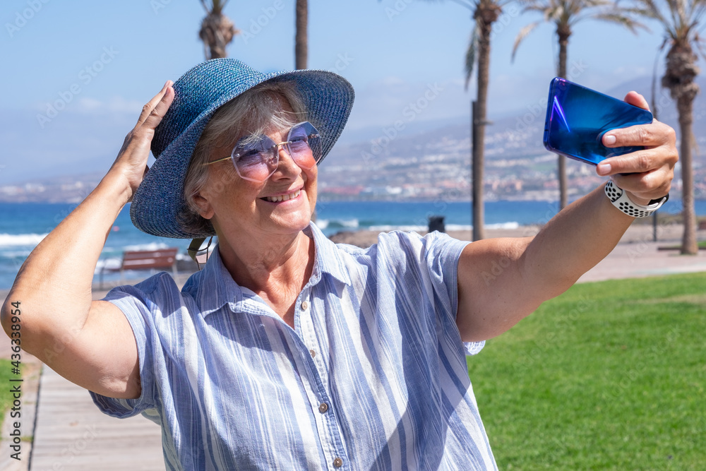 Happy senior woman at sea enjoying summer holidays. Handsome  influencer lady in video streaming