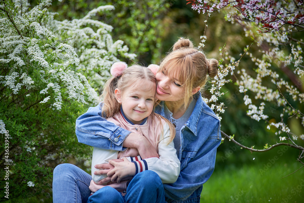 Fototapeta premium Handsome blonde mother and child daughter together in a blossom park