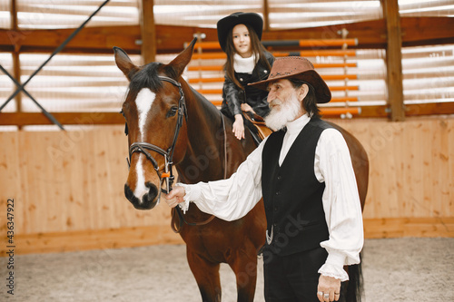 A little child riding a horse with an instructor