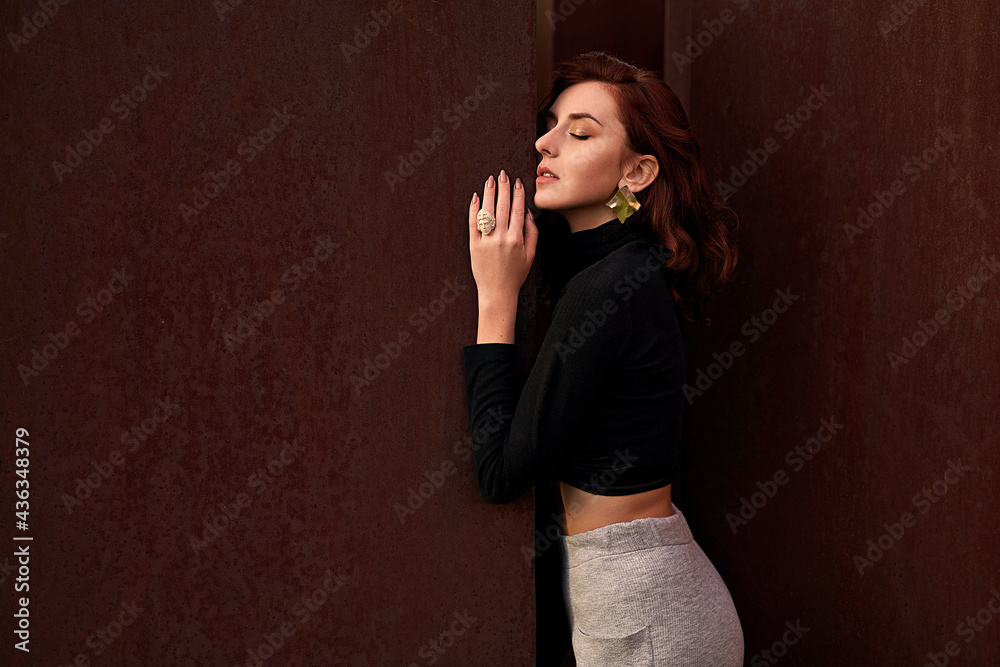 Portrait of a beautiful young woman with closed eyes between two rusty walls. Mental health of psychology concept.