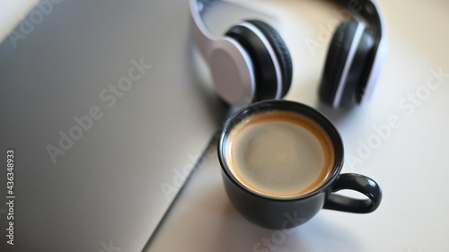Top view shot of Coffee mug with laptop and headphone on placed on a table in a cafe.