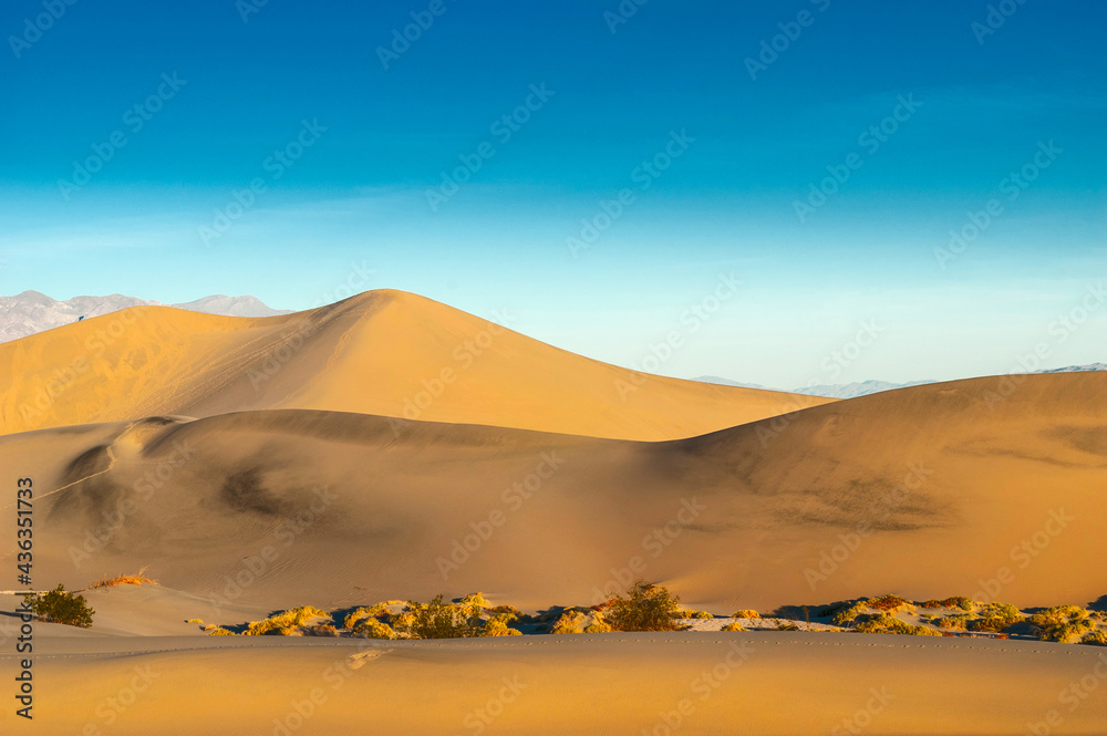 Sand dunes against a blue cloudy sky.