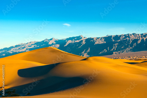 Desert with sand dunes and rocks in the background.