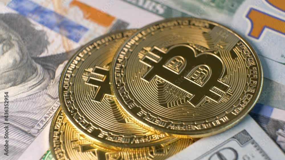 Close up of metal shiny bitcoin crypto currency coins on US dollar bills. Electronic decentralized money concept.