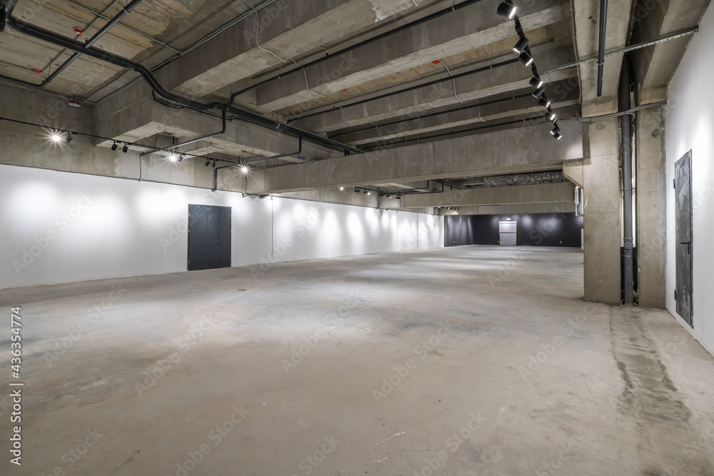 empty interior of large concrete room as warehouse or hangar with spotlights empty interior of large concrete room as warehouse or hangar with spotlights