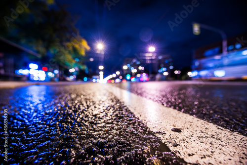 Night city after rain, the headlights of passing cars racing. Wide angle view of the level of the dividing line