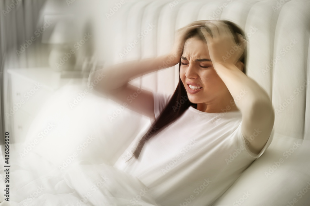 Young woman suffering from migraine in bed at home Young woman suffering from migraine in bed at home