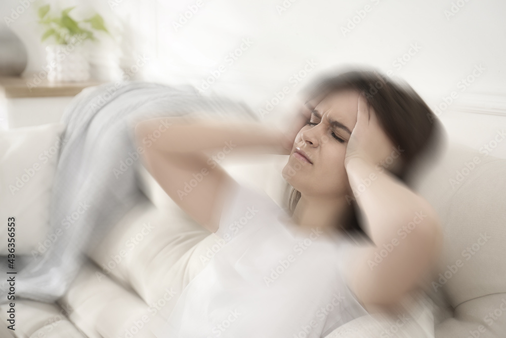 Young woman suffering from migraine on sofa at home Young woman suffering from migraine on sofa at home