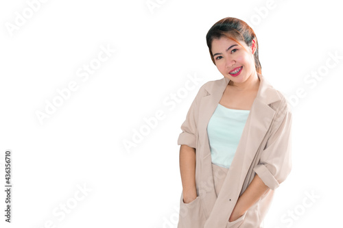 An Asian woman standing with her hand in her pocket and smiling.