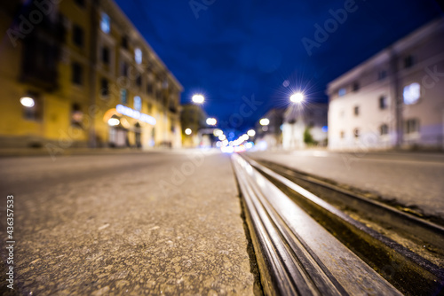 Night highway with rails  the glowing lights of approaching cars. Wide angle view of the level of the rails