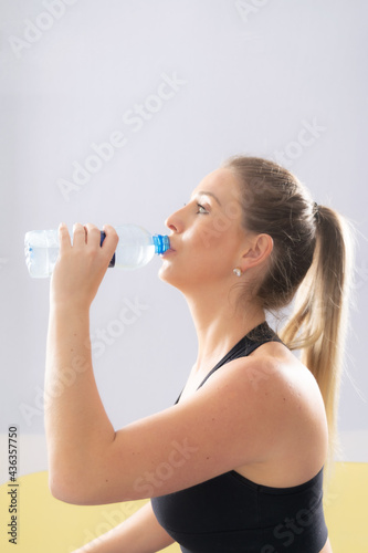 Fitness woman drinking water, white backgound, high key.