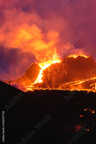 Person going downhill with Volcanic Eruption in the background - Geldingadalur, Iceland