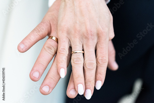 Close up of clasped hands with wedding rings. Marriage symbol. Gold wedding rings on the fingers of the newlyweds.