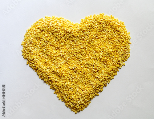 A pile of Hulled-split Mung Bean (Yellow beans) in the shape of a heart on the white background, Full depth of field.