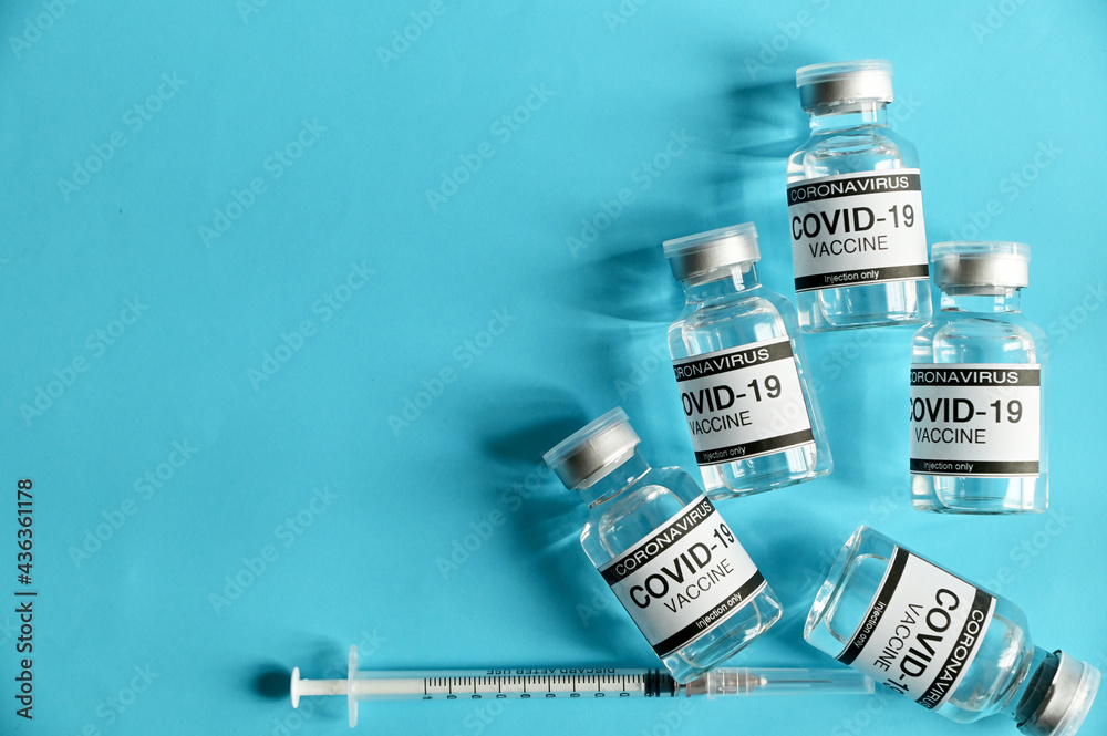 Coronavirus COVID-19 Vaccine Glass Bottle and syringe on blue surface with blue background at Thailand. Concept viruses spread throughout the world. Selective Focus. Coronavirus COVID-19 Vaccine Glass Bottle and syringe on blue surface with blue background at Thailand. Concept viruses spread throughout the world. Selective Focus.