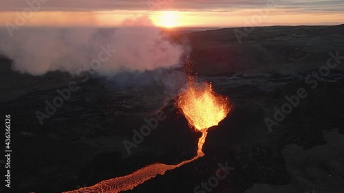 Fountain of magma and lapilli erupting from volcano crater at sunset, Iceland. Aerial static photo