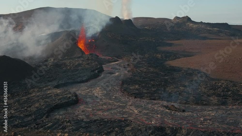Magma spurts from crater fissure of erupting volcano on sunny day, Iceland. Static view photo