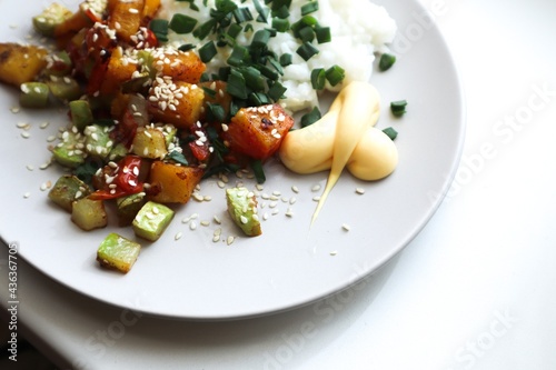 Rice with stewed vegetables on a plate. Vegetables sprinkled with sesame seeds 
