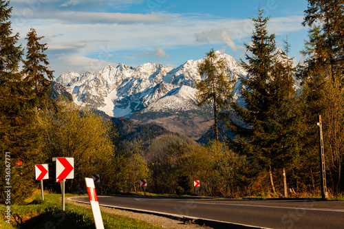 Beautiful view of the snow-capped peaks of the Tatra Mountains. The road leading towards the mountains. Afternoon warm sun. Poland.