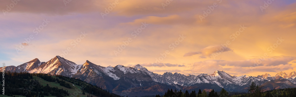 A beautiful panorama of the Bielskie Tatras. White mountain peaks in the distance Beautiful colors of the sky. View at sunset. Jurgow, Poland