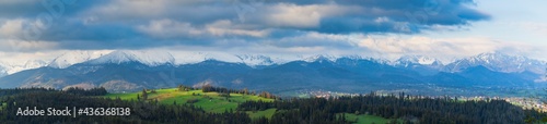 A beautiful panorama of the entire range of the Tatra Mountains. The colorful rays of the sun illuminate the snow-covered  white mountains. The view at sunrise. Poland