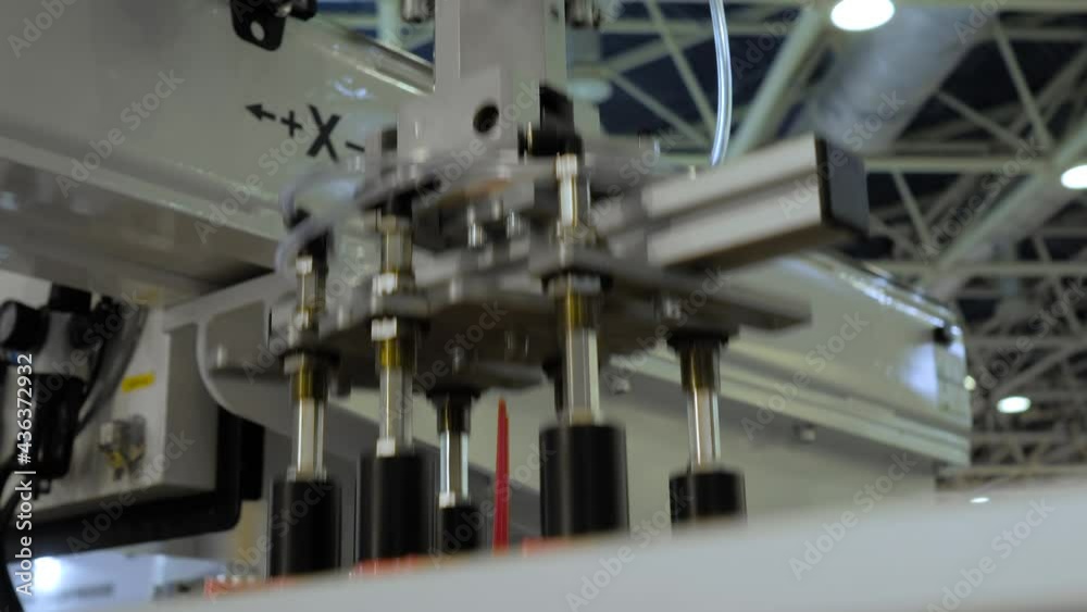 Automatic pick and place robotic arm manipulator with suction cups moves red plastic cookie cutters - part of plastic injection molding machine at exhibition. Manufacturing, production concept Automatic pick and place robotic arm manipulator with suction cups moves red plastic cookie cutters - part of plastic injection molding machine at exhibition. Manufacturing, production concept