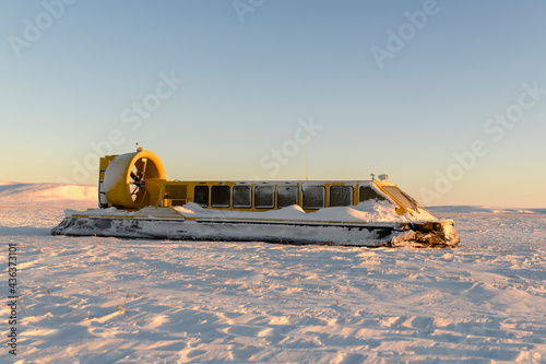 Hovercraft in winter tundra. Air cushion on the beach. Yellow hover craft under snow. photo