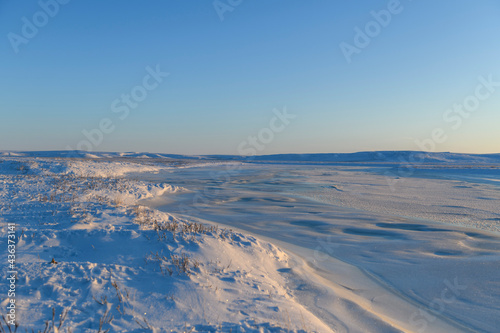 Arctic landscape in winter time. Small river with ice in tundra. Sunset. © Alexey Seafarer