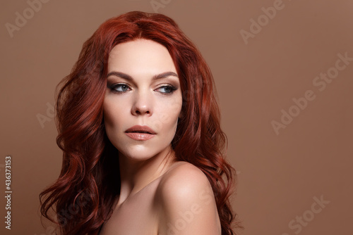 Red-haired beautiful woman on a beige background.