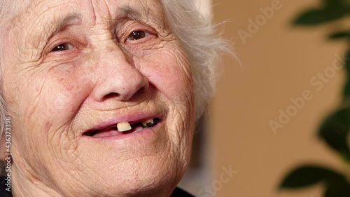 sweet toothless elderly woman turns her head and smiles at the camera photo