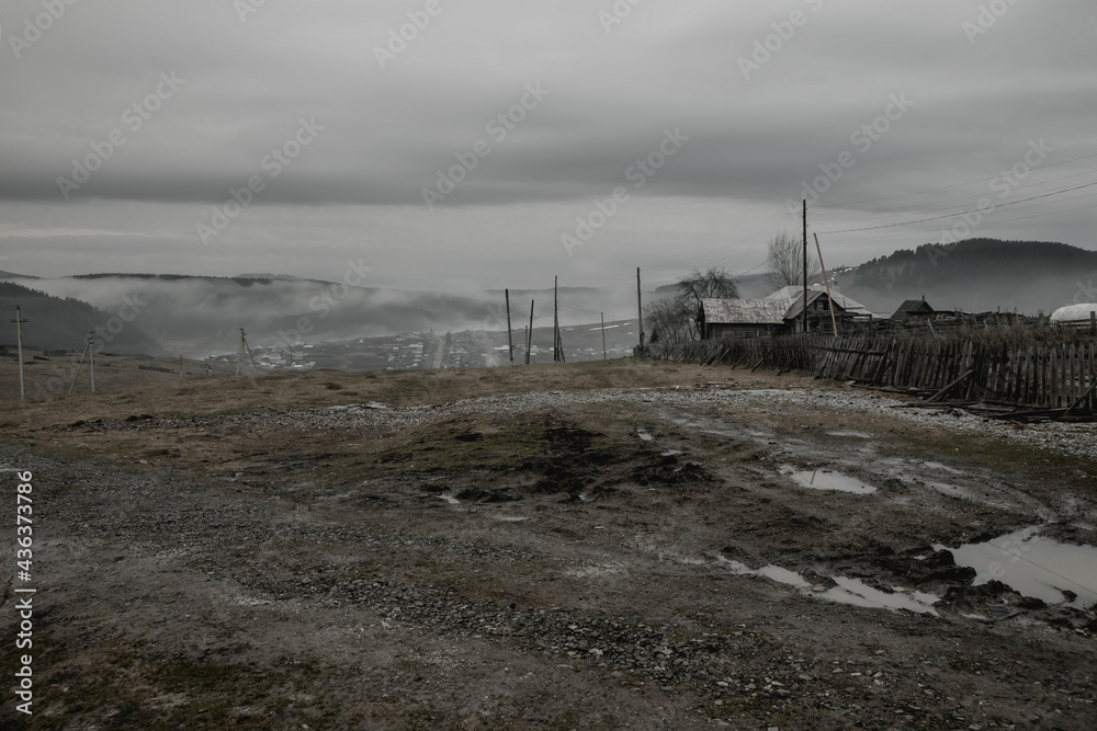 Rural mountain landscape. Beautiful fog, mountains and forest. Village in the valley. A rainy gray day.
