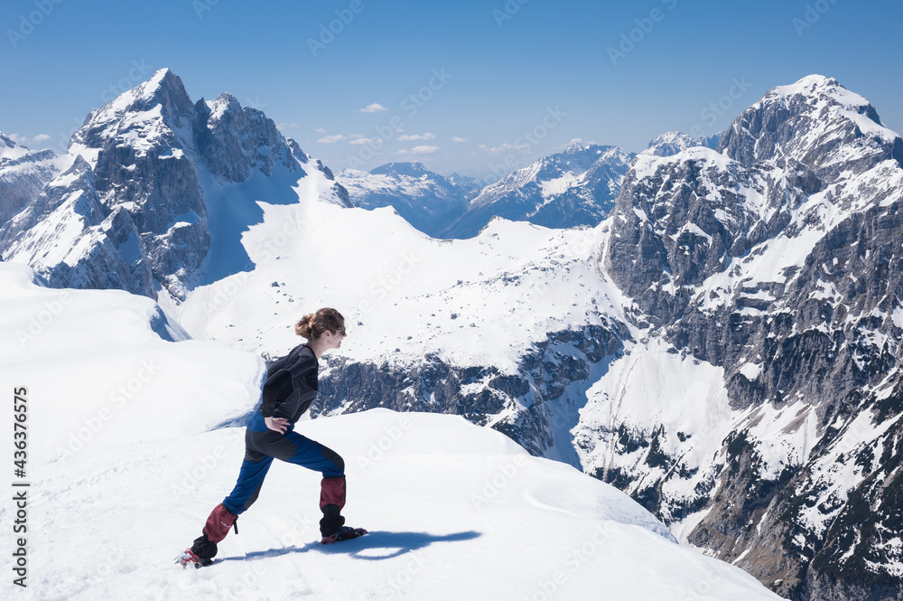 slender positive smiling girl climber mountaineer on a snowy alpine slope
