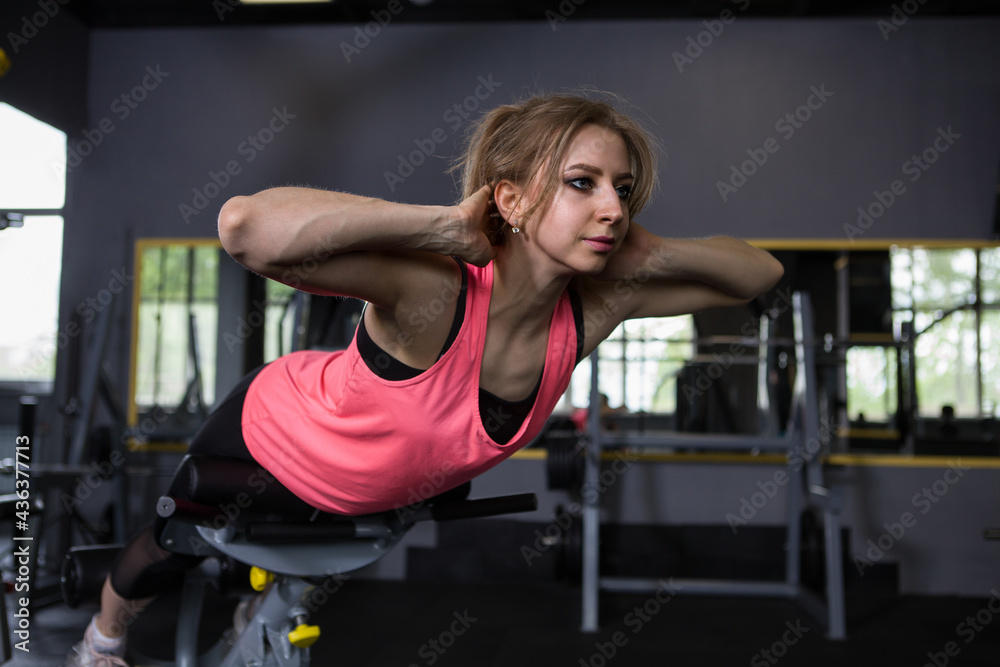 Fototapeta premium Young woman doing hyperextension exercise at the gym