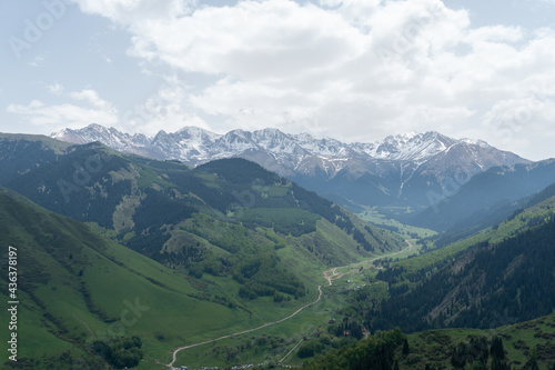 Endless steppe in the valley at the foot of the mountains, bathed in bright sunlight. Amazing view on green mountains. mountain, covered with green trees, under a blue sky with clouds.