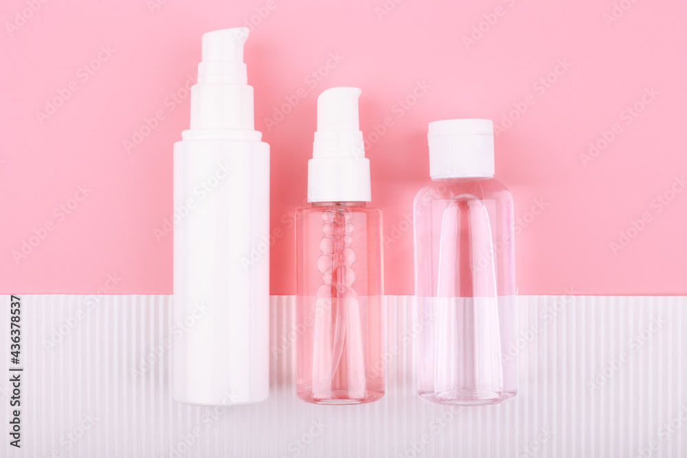 Top view of set of cosmetic tubes against pink background and white paper with stripes. Concept of skin care and beauty Top view of set of cosmetic tubes against pink background and white paper with stripes. Concept of skin care and beauty