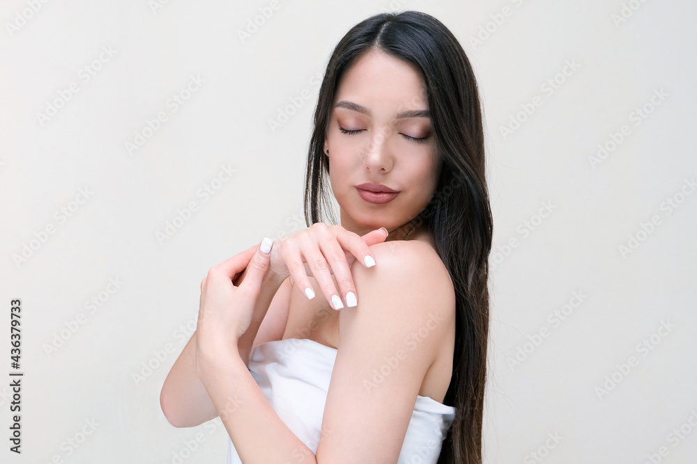 Skin and body care. Beautiful young woman in a towel touches her skin Skin and body care. Beautiful young woman in a towel touches her skin