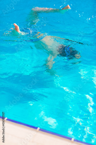 Cute happy little boy in goggles swimming and snorking in the swimming pool