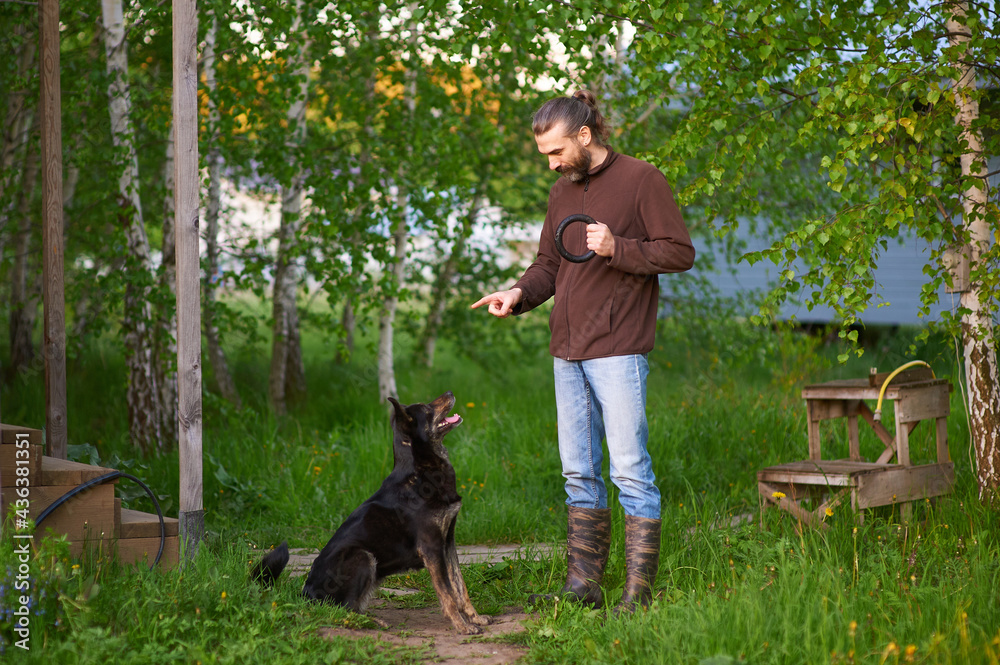 A man is teaching his dog hand signals. A verbal command and hand signals for dog. Training technique and communication with pet A man is teaching his dog hand signals. A verbal command and hand signals for dog. Training technique and communication with pet