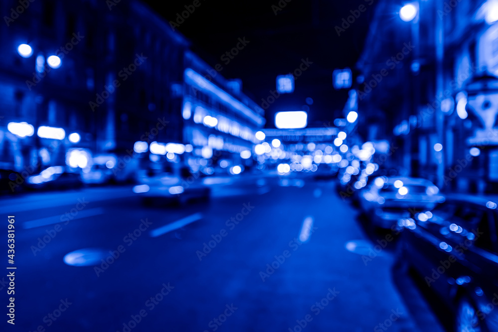 Nights lights of the big city, car go down the avenue past the bright shop windows. Wide-angle view, defocused image