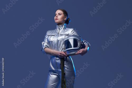 Young spacewoman in silver suit holding helmet photo