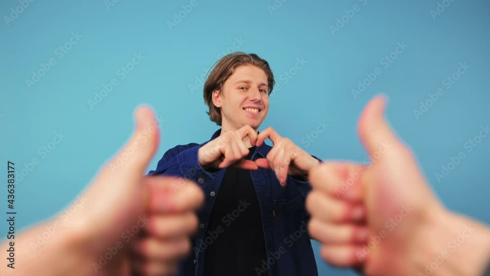 Third person hands pointing index finger at positive young man standing