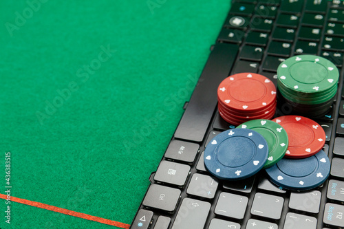 Gambling chips on computer keyboard on green background photo