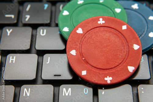 Gambling chips on computer keyboard on green background