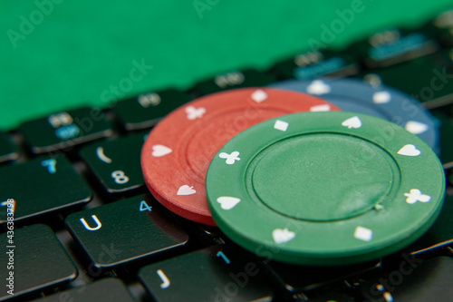 Gambling chips on computer keyboard on green background