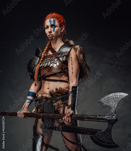 Violent scandinavian woman in armour holding an axe in dark background © Fxquadro