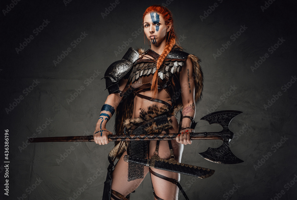 Charming woman viking holding an axe in dark background Charming woman viking holding an axe in dark background