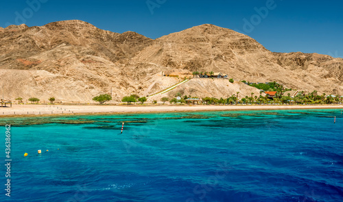 Beautiful coral reefs of the Red Sea, sandy beaches, tourist resort hotels and mountains near Eilat, Israel. Waterfront view for Web banner