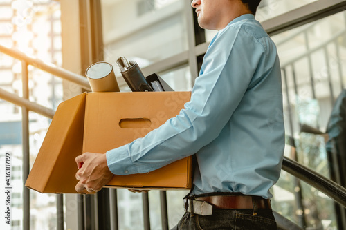 Businessman is carrying a brown cardboard box to resignation photo